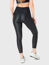 Calza deportiva negra con tela brillante, tiro alto y cintura en forma de "V" con silicona interior.
