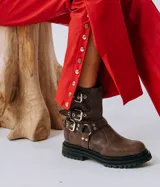 Botas cortas de cuero color marrón con suela track, caña baja y múltiples correas con hebillas metálicas.