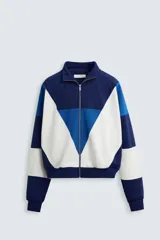 Chaqueta deportiva azul marino, azul y blanca con cuello alto, cierre frontal con cremallera, bolsillos laterales y puños y bajo acanalados.