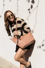 Cartera negra tipo shopper con textura símil cuero, doble asa de hombro y llavero colgante con forma de corazón.