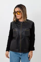 Campera negra con cuerpo de cuero y mangas de tejido de punto. Tiene cuello redondo, cierre frontal con cremallera, dos bolsillos con cremallera en el pecho y costuras decorativas en los hombros.