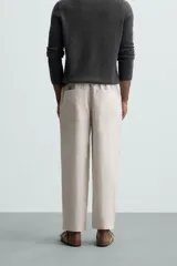Pantalón negro de lino, corte recto y relaxed fit, con cintura elástica ajustable con cordón, bolsillos laterales y traseros.