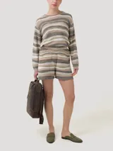 Short tejido de punto a rayas horizontales en tonos beige, blanco y marrón. Cuenta con cintura elástica y forro interno. El ruedo tiene un detalle calado.