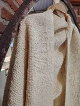 Chal color crudo tejido en lana artesanalmente, con flecos en los extremos.