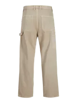 Pantalón jean color arena, de corte amplio, tiro alto y diseño de carpintero con múltiples bolsillos.