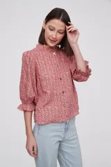 Blusa estampada con flores azules y hojas verdes, cuello mao con volados, mangas 3/4 con volados en los puños y cierre frontal con botones.
