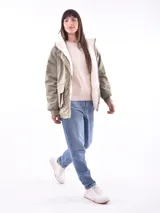 Campera color beige con interior de piel sintética blanca, capucha, cierre frontal con botones a presión, bolsillos laterales con solapa y puños elásticos.