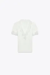 Camiseta blanca de algodón con textura de canalé, escote en pico y mangas cortas. Detalle de encaje blanco en escote y mangas.