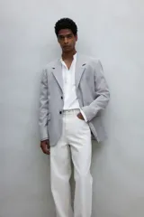 Camisa blanca de corte estándar, con cuello mao, tapeta clásica, canesú en la espalda, mangas largas con puños abotonados y bajo redondeado.