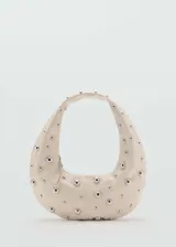 Bolso de hombro color crema con tachuelas plateadas.