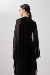 Capa tejida color negro con flecos en el borde inferior.