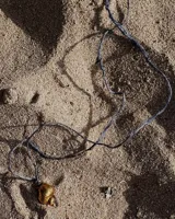 Collar con dije de caracola dorada y cordón fino azul.