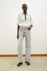 Jeans de tiro alto color negro lavado, con cintura cruzada, cinco bolsillos y pernera recta. El bajo está acabado en vuelta y tiene cierre frontal cruzado con cremallera y botones.