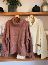 Sweater de punto color ladrillo, con cuello alto y mangas largas con puños acampanados. Decorado con perlas sintéticas en el frente y en los puños.