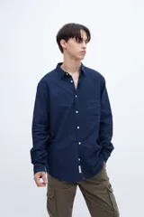 Camisa azul marino de algodón, corte regular fit, con cuello solapa clásico, bolsillo en el pecho y botones blancos.
