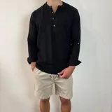 Camisa blanca de muselina con cuello mao y manga larga con puños abotonados.