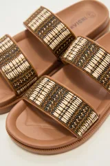 Sandalias tipo slide de plataforma color marrón, con dos tiras anchas sobre el empeine decoradas con tejido de rafia en tonos marrón, negro y beige.
