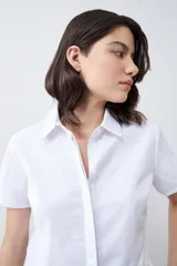 Camisa blanca de corte clásico, con cuello y mangas cortas.