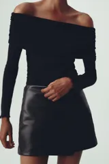 Falda pantalón corta negra de cuero sintético, tiro medio y corte cruzado.