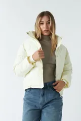 Campera corta color crema con cuello alto y cierre frontal con botones a presión.