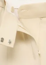 Conjunto color crema compuesto por un blazer de doble botonadura con solapas de muesca y bolsillos de parche, y un pantalón de corte wide leg con pinzas y cierre oculto.