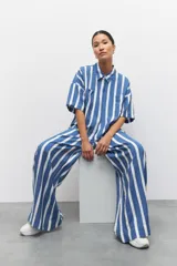 Pantalón largo azul con rayas verticales blancas, de corte amplio, con cintura elastizada y cordón ajustable.