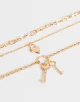 Set de tres collares dorados de diferentes largos, con eslabones de distintos tamaños. Incluye un dije de corazón y un dije de llave.