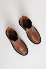Botas Chelsea color marrón de cuero sintético, con elástico lateral negro, suela track negra y tirador trasero.