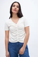 Remera color crudo con escote en V, cartera de botones y frunces.