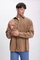 Sobrecamisa de pana color tostado, de corte recto, con cuello camisero, cierre frontal con botones, dos bolsillos de parche en el pecho y mangas largas con puños abotonados.