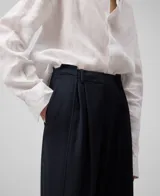 Pantalón de vestir azul marino con pinzas asimétricas, corte ancho y bolsillos de vivo en la parte trasera.