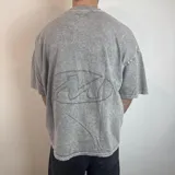 Remera gris con efecto acid wash, corte boxy fit y logo ovalado en la espalda.