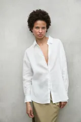 Camisa blanca de lino con corte clásico, cuello camisero y mangas largas.