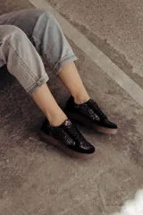 Zapatillas bajas color beige con estampado de piel de serpiente metalizada, cordones blancos y suela color caramelo.