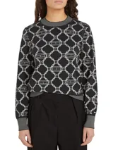 Sweater azul marino con diseño de rombos blancos con el logo de la marca en el centro. Tiene cuello redondo, puños y bajo acanalados.