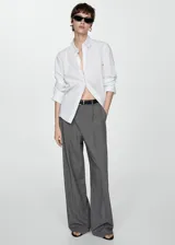 Pantalón gris con finas rayas verticales blancas, de corte wide leg, con trabillas, pinzas y bolsillos laterales.