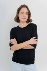 Buzo de punto liviano color negro, de diseño oversize con cuello redondo y mangas 3/4. Presenta terminaciones acanaladas en cuello, puños y cintura.