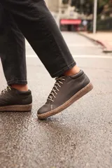 Zapatillas acordonadas de cuero color negro con suela marrón. Diseño artesanal de producción local.