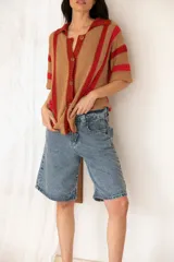 Camisa tejida a rayas horizontales color tostado y rojo, con cuello polo, mangas cortas y botones frontales.