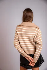 Sweater de punto color beige con rayas horizontales blancas, cuello polo con cierre de cremallera y mangas largas.