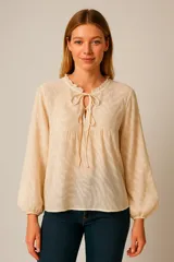 Blusa color crema con estampado de cebra, cuello mao con volantes y lazo, mangas largas abullonadas con puños elásticos.