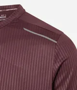 Remera deportiva de manga corta y cuello redondo, color beige claro, con textura acanalada vertical. Presenta detalles reflectantes en los hombros.