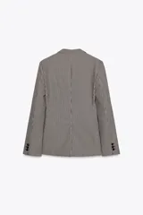 Blazer de cuello solapa y manga larga con estampado de cuadros en tonos marrón y blanco. Tiene bolsillos con solapa en el delantero, abertura en la espalda y cierre frontal con botones.