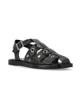 Sandalia tipo cangrejera en cuero graneado color negro, con ornamentos metálicos y hebilla ajustable.