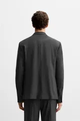 Blazer slim fit color gris oscuro confeccionado en tejido con viscosa. Tiene cuello con solapas de muesca, manga larga con puño abotonado, bolsillo de vivo en pecho, bolsillos de solapa en cadera, bolsillo interior, bajo con aberturas en espalda y cierre frontal con botones.