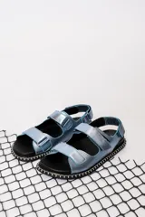 Sandalia chata de diseño moderno, con tiras en tonos azul celeste y negro.