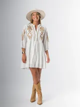 Vestido corto blanco de algodón italiano con bordado azul, mangas tres cuartos y botones frontales.