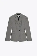 Blazer gris jaspeado de cuello solapa y manga larga con hombreras. Tiene bolsillos delanteros con solapa y cierre frontal cruzado con botones.