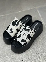 Sandalias tipo sueco con plataforma de goma negra y tira ancha de cuero con estampado animal print de vaca.