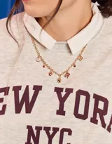 Collar corto dorado con cadena de eslabones y dijes colgantes de corazones, tréboles, letras y piedras rojas.